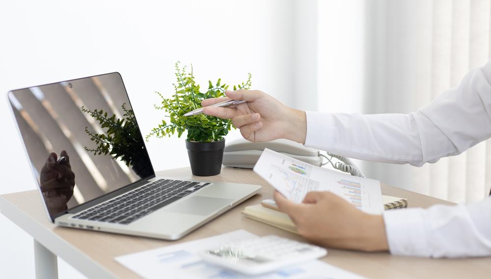 Consultor apresentando indicadores de vendas em um relatório ao lado de um notebook